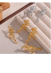 Detailed close-up of bow-knot earrings with inlaid rhinestones in gold and silver finish