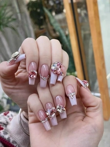 Close-up of long coffin fake nails with pink heart-shaped rhinestones and 3D crystal accents