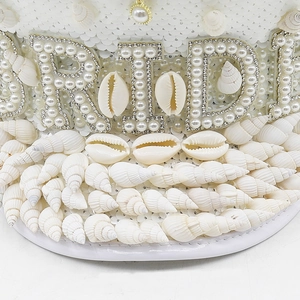 Detail of white sequin bride hat with pearl BRIDE text and marine seashell accents