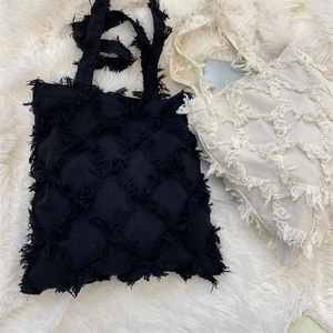 Detailed view of canvas tote bags with fringed diamond patterns in black and beige colors