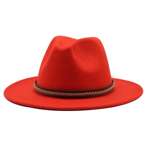 Detail of red wool jazz hat featuring a brown leather braided band on white background