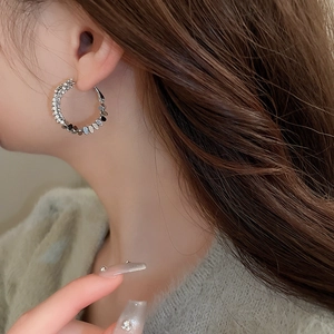 Close-up of a silver geometric hoop earring with sparkling zircon inlay on model