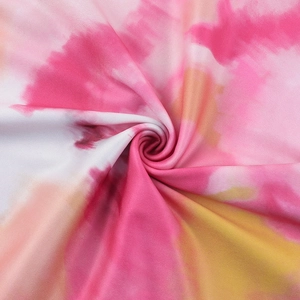 Close-up detail of tie-dye fabric with pink and orange gradients on high-density knit dress