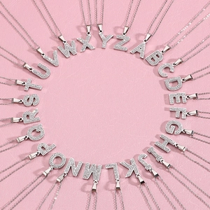 Full set of 26 alphabet initial necklaces with crystal pavé pendants on pink background