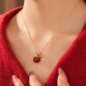 Primo piano della collana con ciondolo a mela in oro 18k e zirconi su una modella