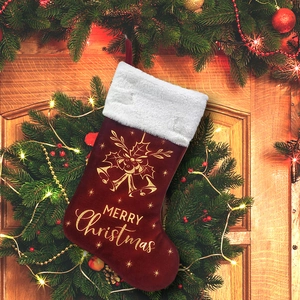 Detail of red velvet Christmas stocking with golden bells and Merry Christmas embroidery