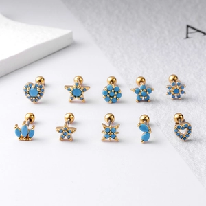 Détail de piercings d'oreille en acier doré avec pierres turquoises en formes de cœur