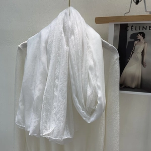 Detail of white lace linen scarf draped over a knit sweater for spring fashion style