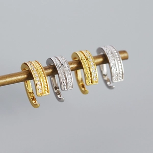 Macro shot of gold and silver twisted spring hoop earrings with micro-inlaid zircon stones