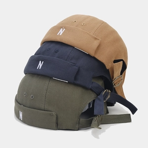 Vertical stack of canvas docker caps in khaki, navy and green with N embroidery