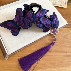 Dettaglio del fermaglio per capelli a farfalla ricamato viola con nappe in seta e ciondolo