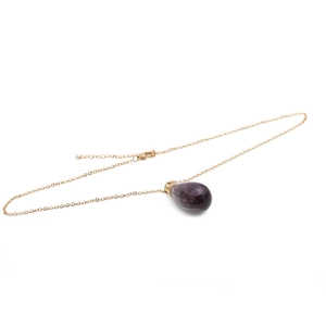 Détail d'un pendentif en pierre violette en forme de goutte avec chaîne dorée