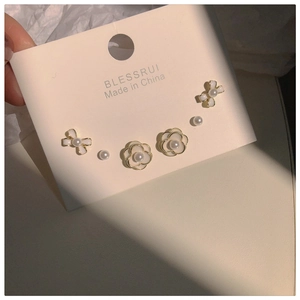 Detail of camellia and pearl earring set with ribbon accents on jewelry card
