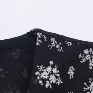 Close-up of black floral fabric texture with white flowers on a layered dress