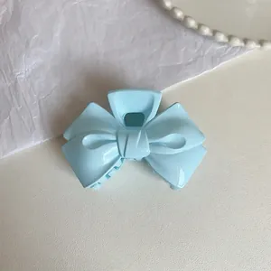 Detailed top view of a light blue cream-colored double bow hair claw clip on a textured surface