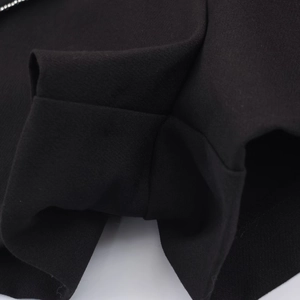 Detailansicht der präzisen Nähte auf dem schwarzen, plissierten Skort-Stoff mit Perlen