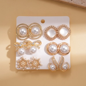 Close-up of 6-pair gold earring set with rhinestones and faux pearls on white card