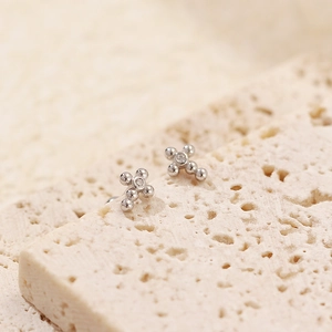 Macro shot of silver S925 cross stud earrings with sparkling cubic zirconia on stone