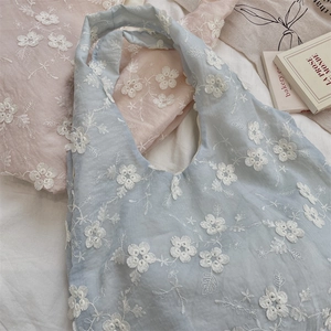 Close-up of floral embroidery on pastel organza tote bags in pink and light blue
