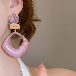 Close-up of geometric resin drop earrings in pinkish-purple marble finish on model