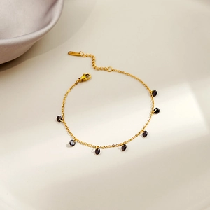 Detail of gold chain bracelet featuring black oval gems and lobster clasp with extender