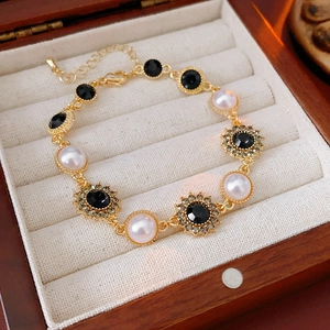 Detailed shot of vintage gold flower bracelet with pearls and black crystals on velvet