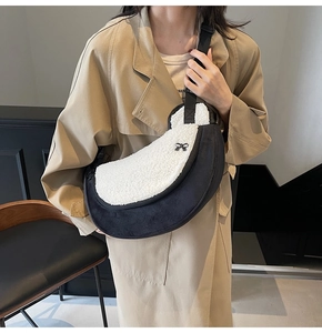 Detail of plush contrast crescent bag with bow accent on a beige trench coat