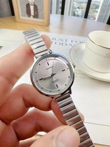 Close-up of minimalist silver chain watch for women held against a cozy book background