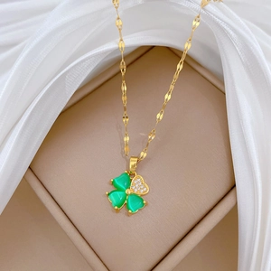 Detail of gold four-leaf clover necklace with green stones and pavé crystals on silk