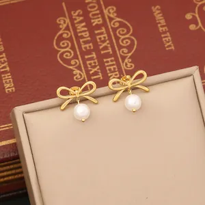 Detail shot of golden bow earrings with white pearl pendants on a vintage jewelry box