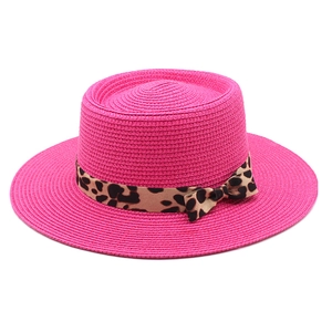 Detail of pink straw sun hat featuring a stylish leopard print ribbon and bow decoration