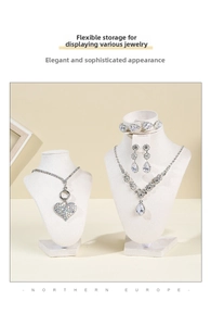 Close-up of beige velvet jewelry bust display stands with sparkling necklace and earrings