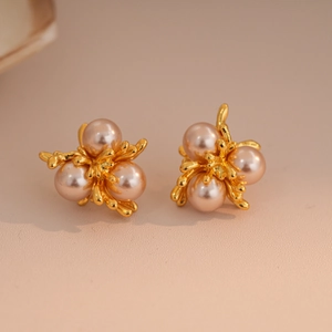 Close-up of gold fireworks coral stud earrings with inlaid pink pearls and zircons