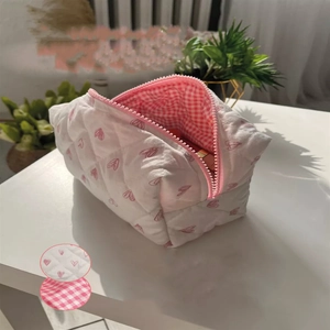 Detailed quilted fabric texture and pink heart pattern on storage makeup bag