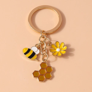 Detail of sunflower and bee enamel keychain charms with vibrant gold dripping oil finish