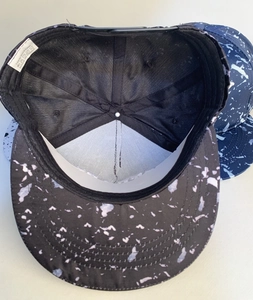 Internal detail of black splatter hip hop cap showing 100% cotton material and label