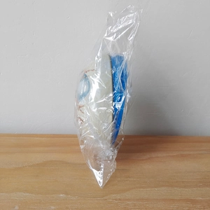 Detail view of Easter tin egg candy container in protective plastic packaging on wood table