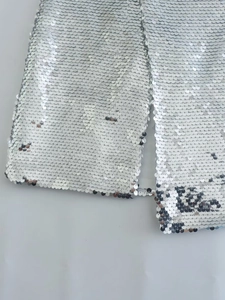 Dettaglio delle paillettes argentate scintillanti e dello spacco su una gonna elegante