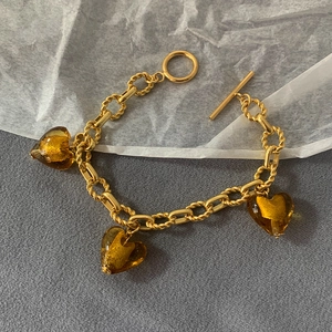 Detail of amber glass heart charms on a gold-plated OT buckle chain bracelet