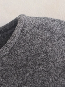 Détail de la texture en laine grise et des coutures sur le col du blouson aviateur