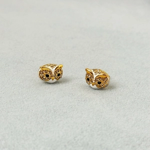 Macro shot of owl stud earrings with gold finish and sparkling crystal accents