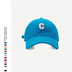 Detail of blue cotton baseball cap featuring textured white towel-embroidered letter C