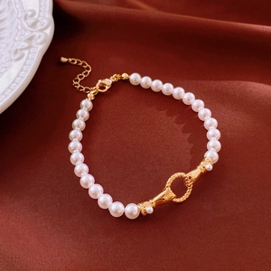 Detailed close-up of a pearl bracelet with gold lobster clasp and adjustable metal chain