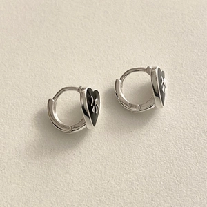 Close-up of silver heart hoop earrings with black enamel and a delicate bow pattern