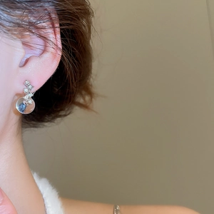 Nahaufnahme von Silberohrringen mit Zirkonia-Anhänger an einem Model getragen
