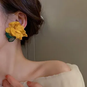 Detail of yellow flower tassel earrings with green leaf and elegant silk fabric petals