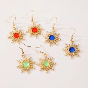 Detail of sun-shaped gold earrings set with red, blue, and light green gemstones