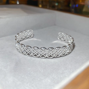 Gros plan détaillé du bracelet ajouré argenté avec motifs floraux et métal poli