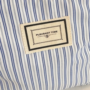 Macro detail of blue and white striped fabric with Pleasant Time fabric label