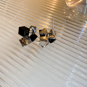 Macro shot of geometric square stud earrings with black and grey crystals on glass